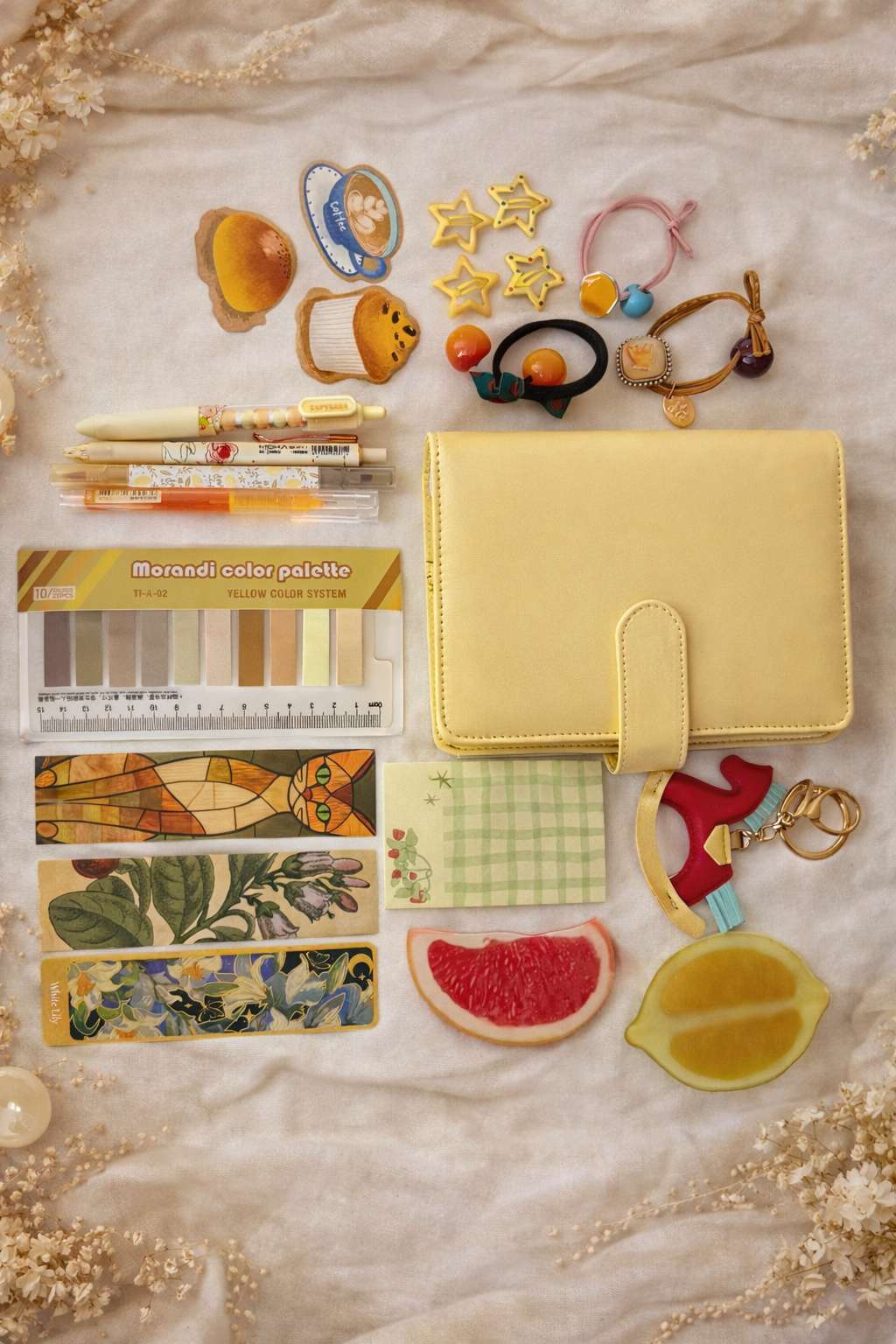 Collection of stationery items including a yellow notebook, colorful bookmarks, and decorative accessories on a marble surface.